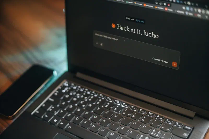 Laptop displaying an artificial intelligence chatbot interface with a smartphone placed beside it.